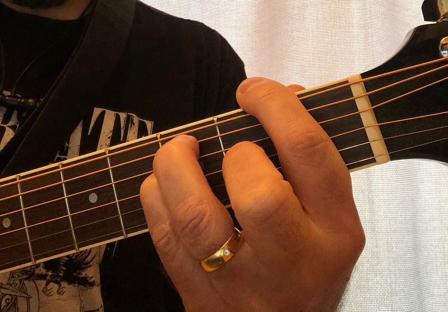 Guitarists hand showing index finger barring the second fret