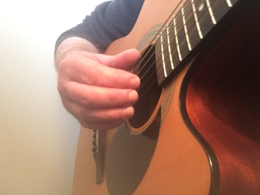 An index finger picking the G string