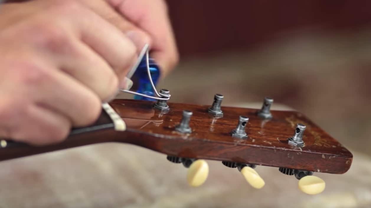 A person re-stringing a guitar